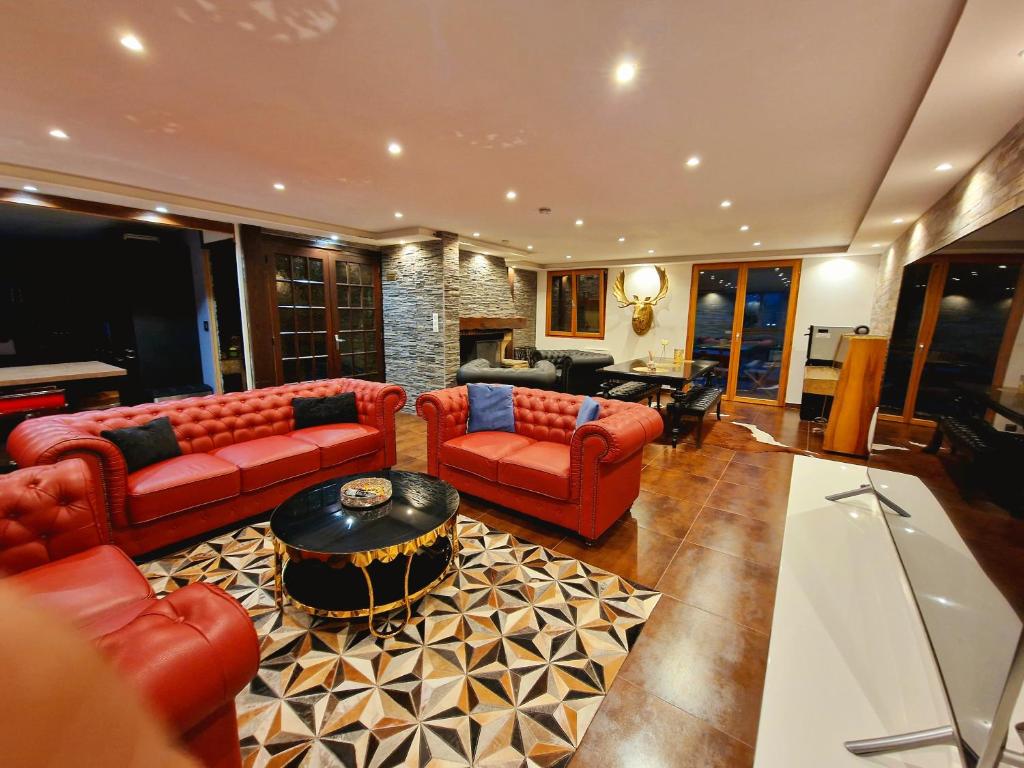 a living room with red couches and a table at Place Royale pour 10 à 12 personnes à 30 mèt des pistes de Ski et Vtt in Métabief