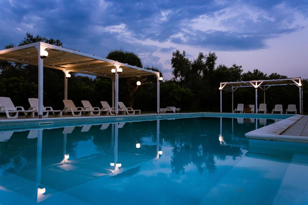 a swimming pool with chairs and a pavilion over it at Il Casale Le Tre Volte in Solfara Mare