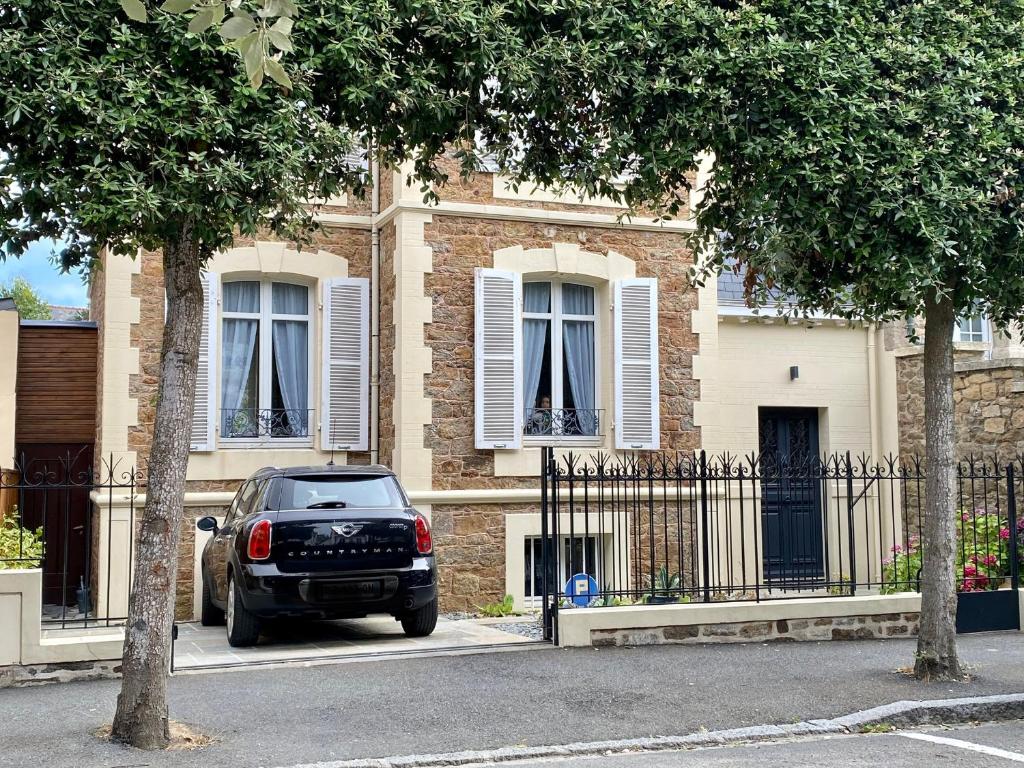una macchina nera parcheggiata di fronte a una casa di Villa Hébert a Saint Malo