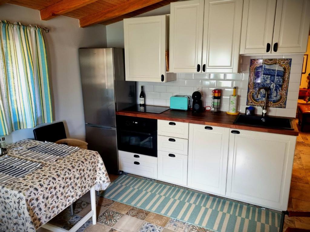 una cocina con armarios blancos y una cama en una habitación en Quinta do Cabril, en Serpins