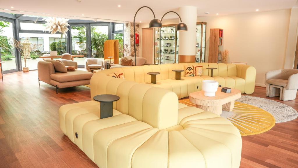 a living room with yellow couches and chairs at Mercure Paris Gare Montparnasse TGV in Paris