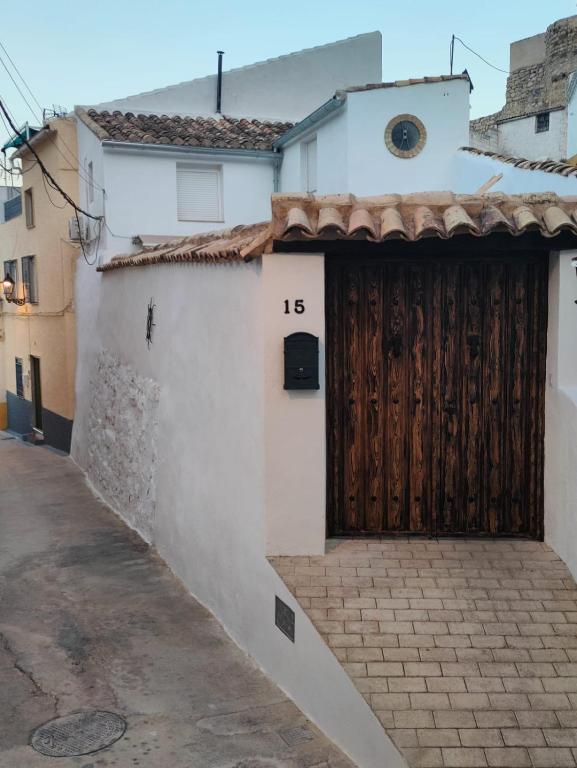 - un bâtiment blanc avec une porte en bois dans une rue dans l'établissement ALOJAMIENTO RURAL EL CARRIL, à Pegalajar
