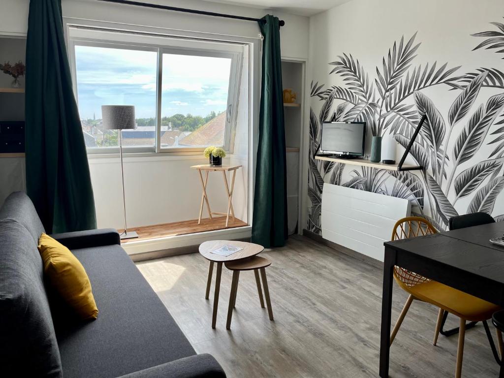 a living room with a couch and a window at Appt centre de Courseulles - 100m de la plage in Courseulles-sur-Mer