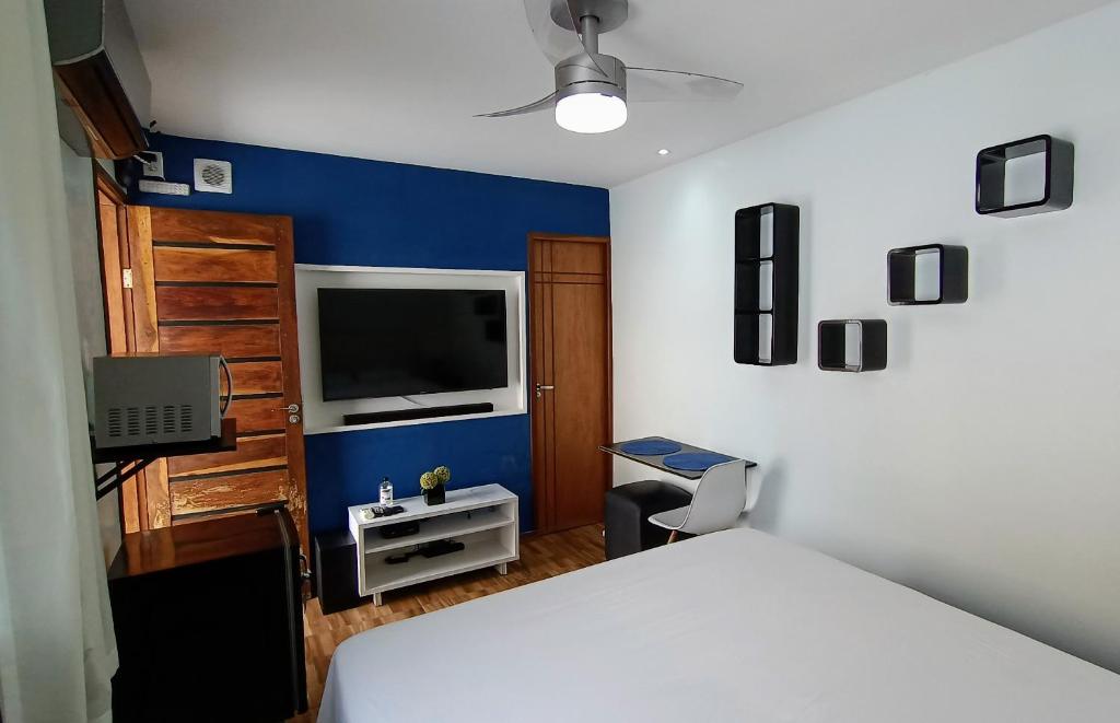 a bedroom with a white bed and a tv at Edícula Próxima a Praias! in São Luís