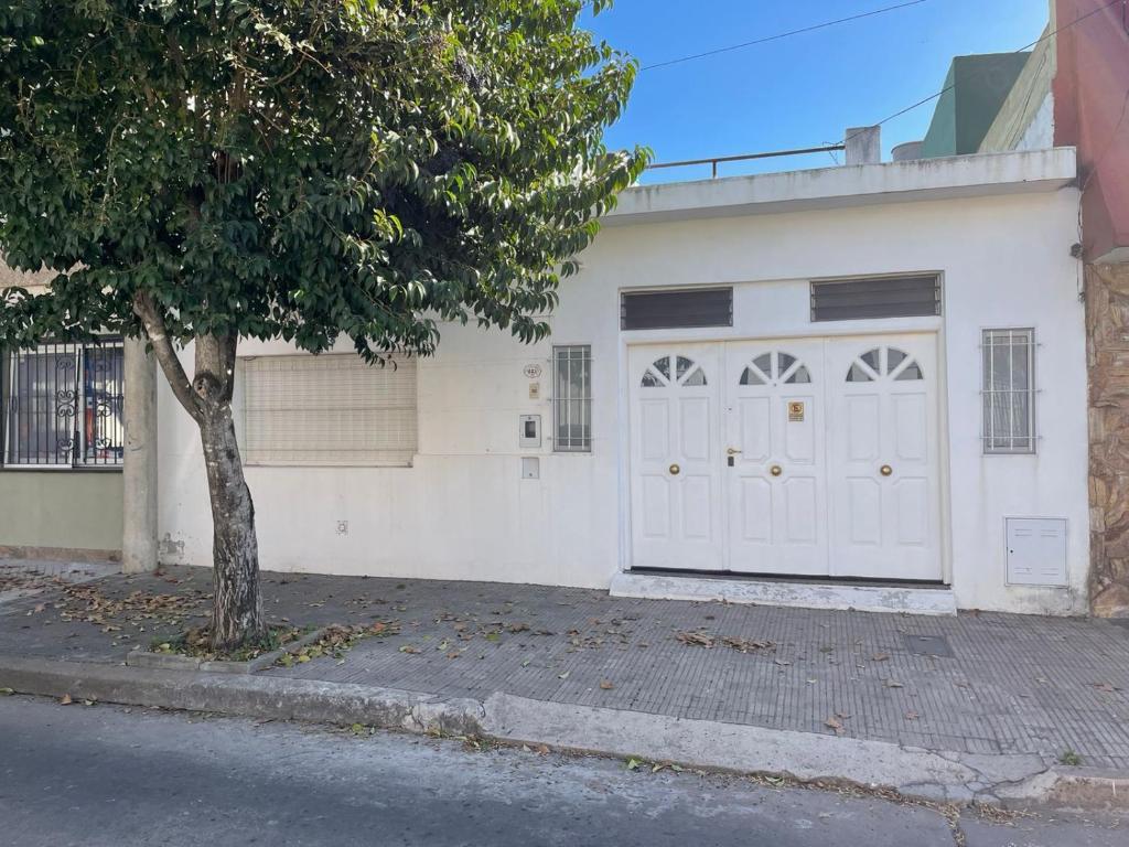 a white garage with a tree in front of it at CASA DEL NARANJO in Rosario