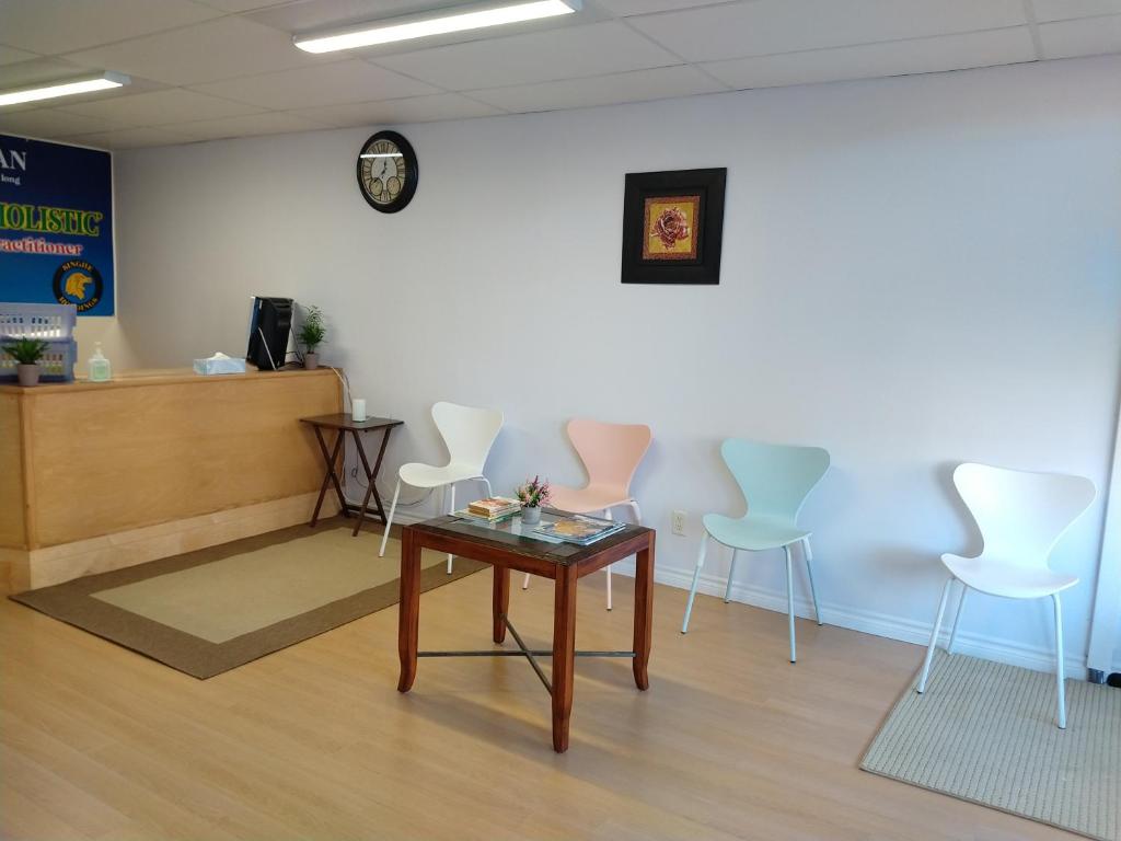 uma sala de espera com uma mesa e cadeiras brancas em Healing Touch Holistic Living Space em Amherst