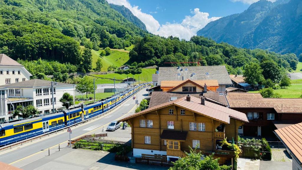 un train circulant dans une rue à côté d'un village avec un train dans l'établissement HOTEL CHRISTINA, à Wilderswil