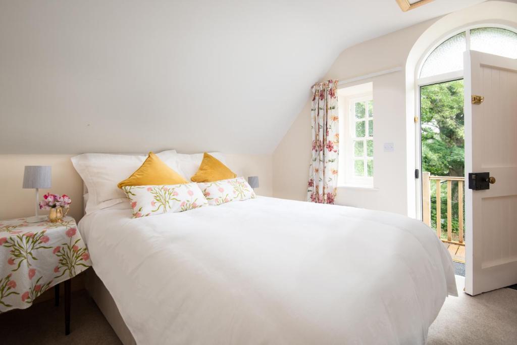 Cama blanca en habitación con ventana en Hethpool Hideaway Northumberland National Park for 2 en Wooler