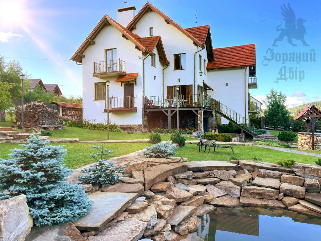 una casa con un estanque delante de ella en Villa Zoryany Dvir en Skhidnitsa