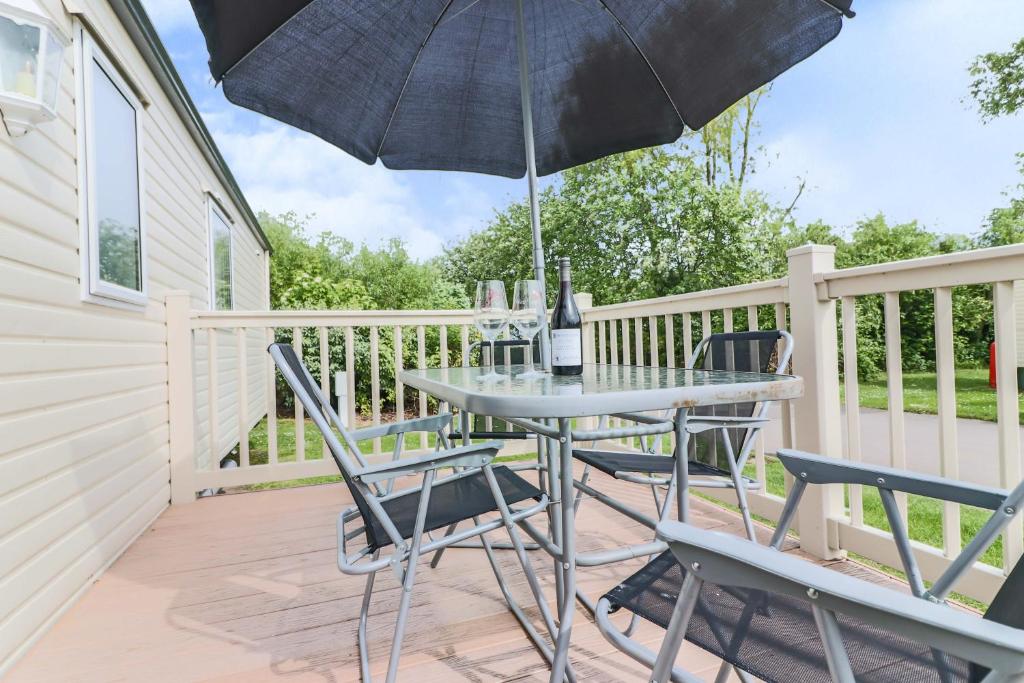 eine Terrasse mit einem Tisch, Stühlen und einem Sonnenschirm in der Unterkunft Fabulous Modern Holiday Home BEACH Cleethorpes Beach Thorpe Park Haven in Cleethorpes