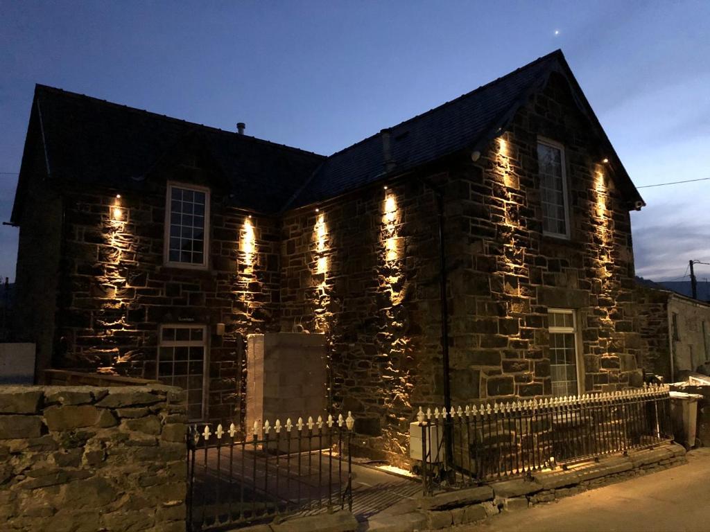 a stone house with lights on the side of it at Glan Aber 1890, snowdonia, Llanrwst in Llanrwst