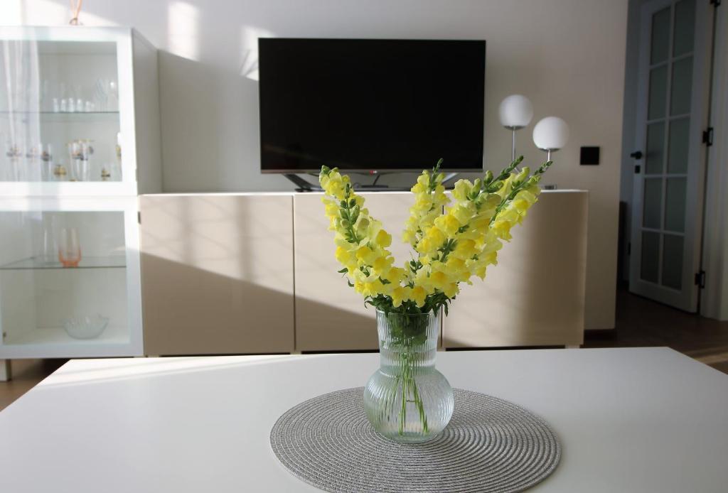 a vase filled with yellow flowers sitting on a table at BAM apartments in Palanga