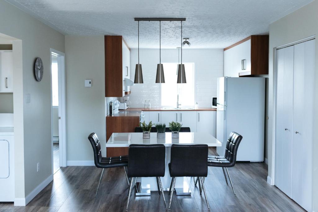 a kitchen and dining room with a white table and chairs at Le Contemporain in Rouyn