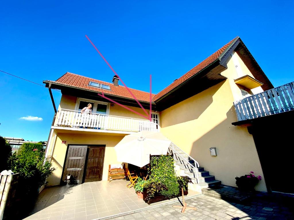 una persona parada en el balcón de una casa con sombrilla en Apartment Sawetz - Ptuj, en Ptuj