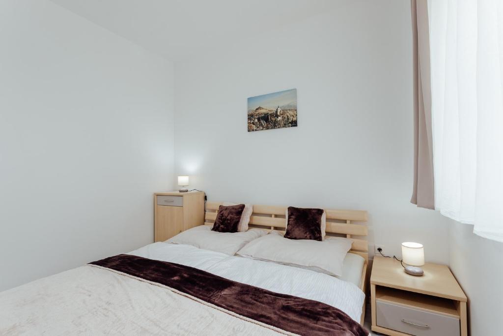 Habitación blanca con cama y mesita de noche en Apartmán vo vile Kammergraf en Banská Štiavnica