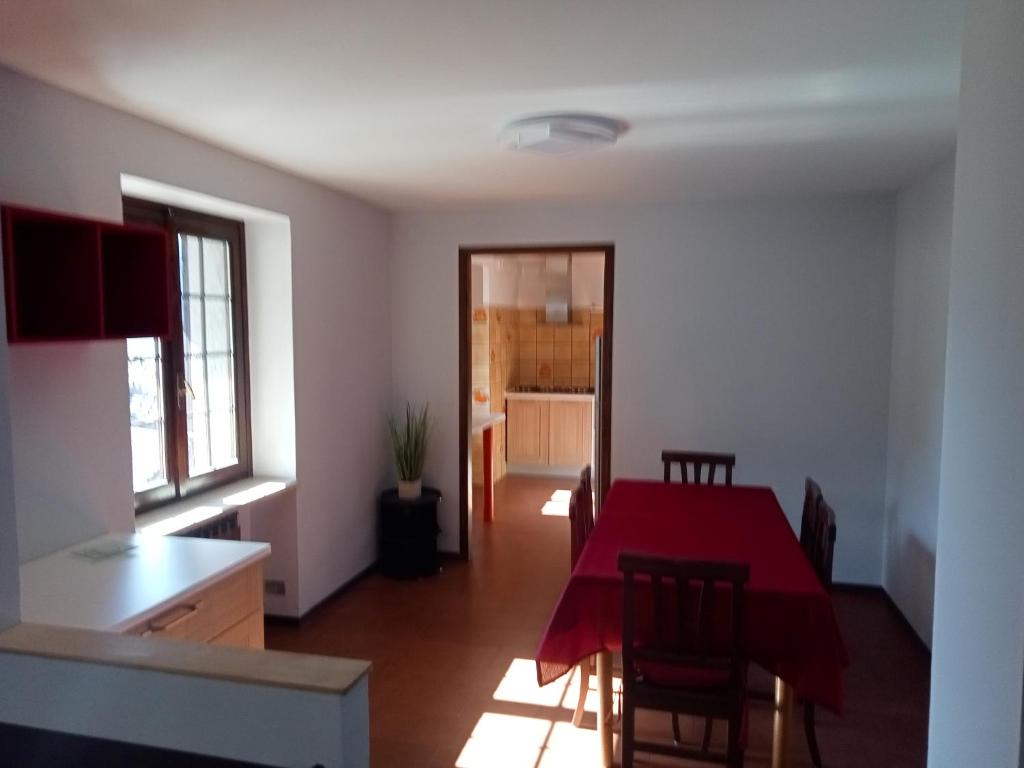 Zimmer mit einem roten Tisch und Stühlen sowie einer Küche in der Unterkunft MAISON BLANC in Aymavilles