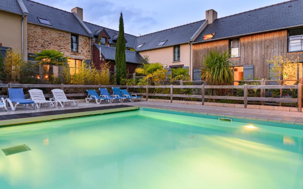 una piscina con sillas y una casa en Lagrange Vacances Les Hauts de la Houle, en Cancale