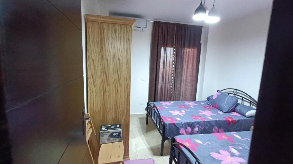 Cette chambre comprend 2 lits et une porte menant à une chambre. dans l'établissement صيف في جراند هيلز الساحل الشمالي, à Al Ḩammām