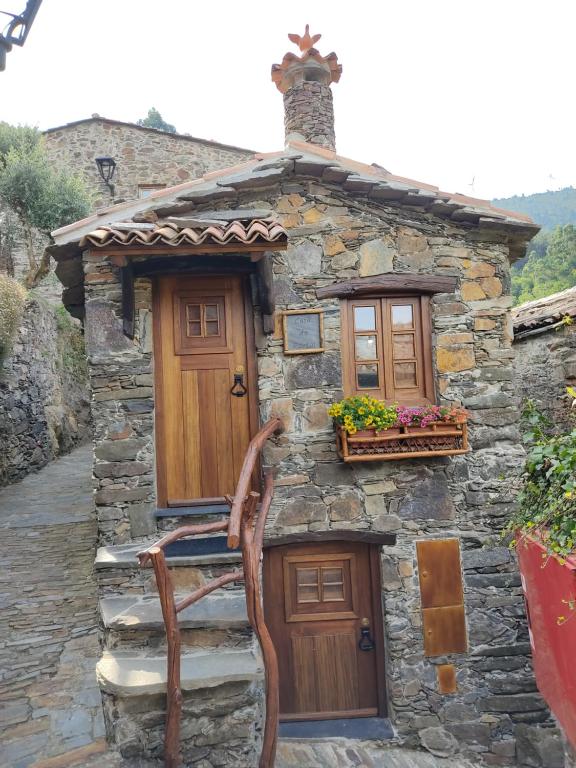 une maison en pierre avec une porte en bois et une fenêtre dans l'établissement Montanhas do Xisto - Casa do Portal, à Lousã