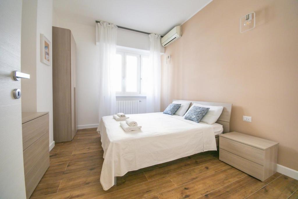 una camera da letto con un letto con lenzuola bianche e una finestra di Vacanze Romane Apartment a Roma