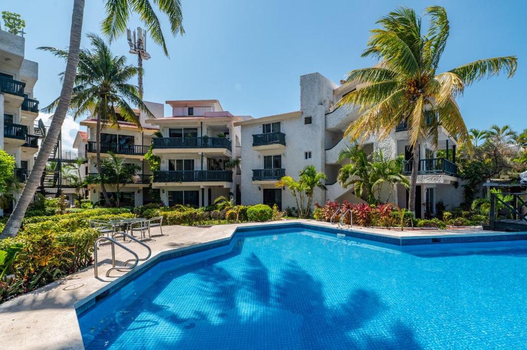 a swimming pool in front of a building with palm trees at Hotel Imperial Laguna Faranda Canc&uacute;n in Canc&uacute;n