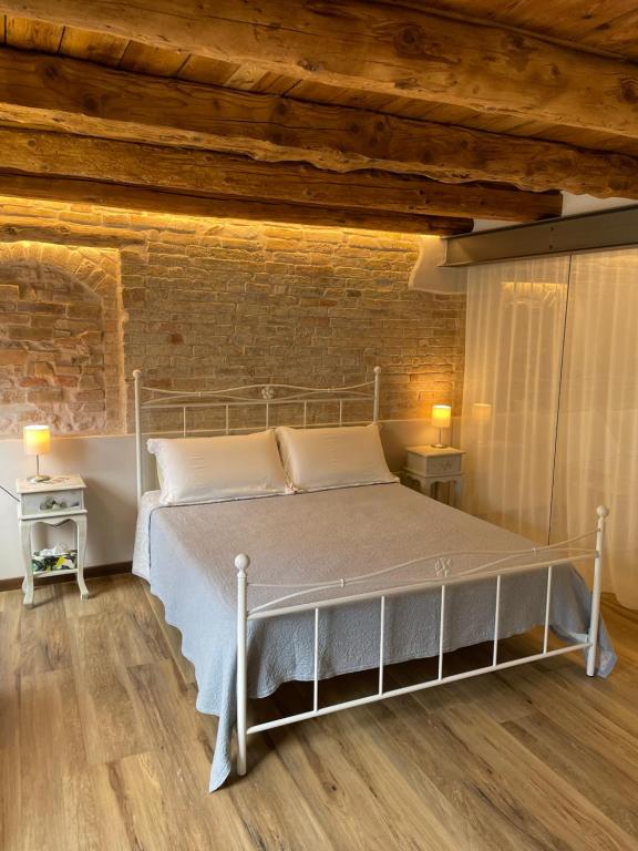 a bedroom with a white bed in a brick wall at Onda Marina B&B Superior in Marano Lagunare
