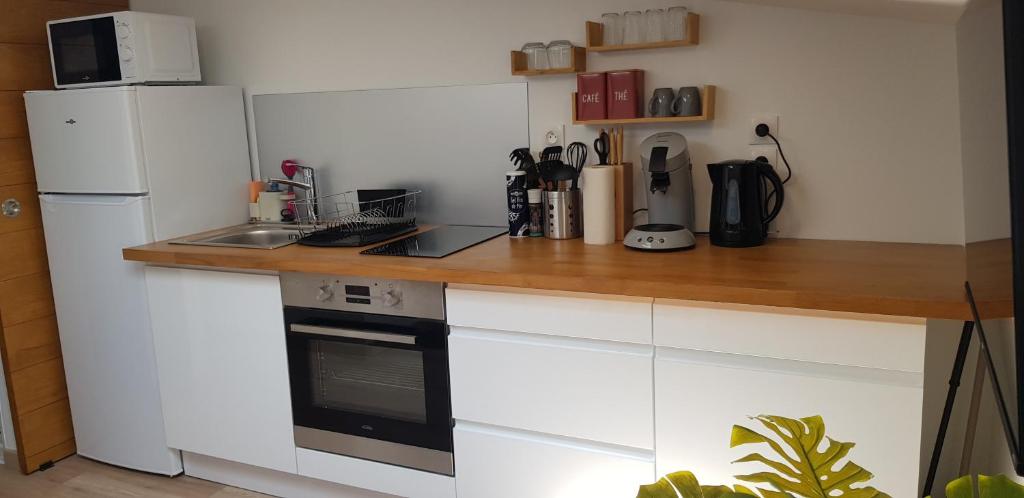 a kitchen with white cabinets and a wooden counter top at Escapade Niortaise - Studios climatisés hyper-centre de Niort in Niort