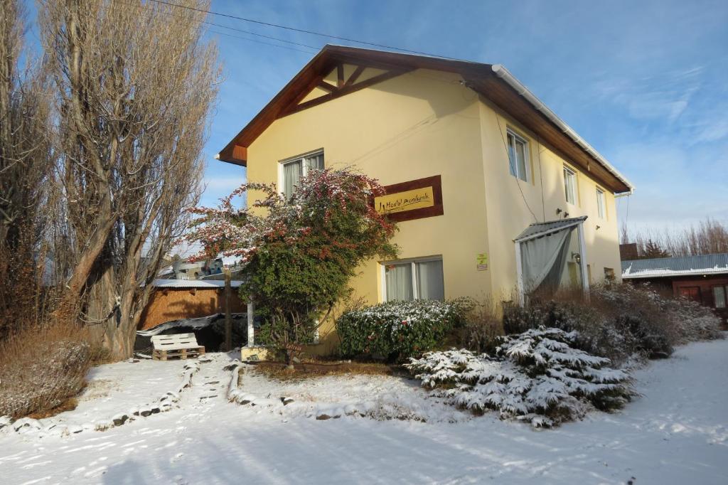 uma casa com neve no chão em frente dela em AONIKENK HOSTEL em El Calafate