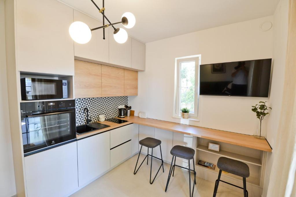 a kitchen with white cabinets and bar stools at Apartment Luka in Zadar