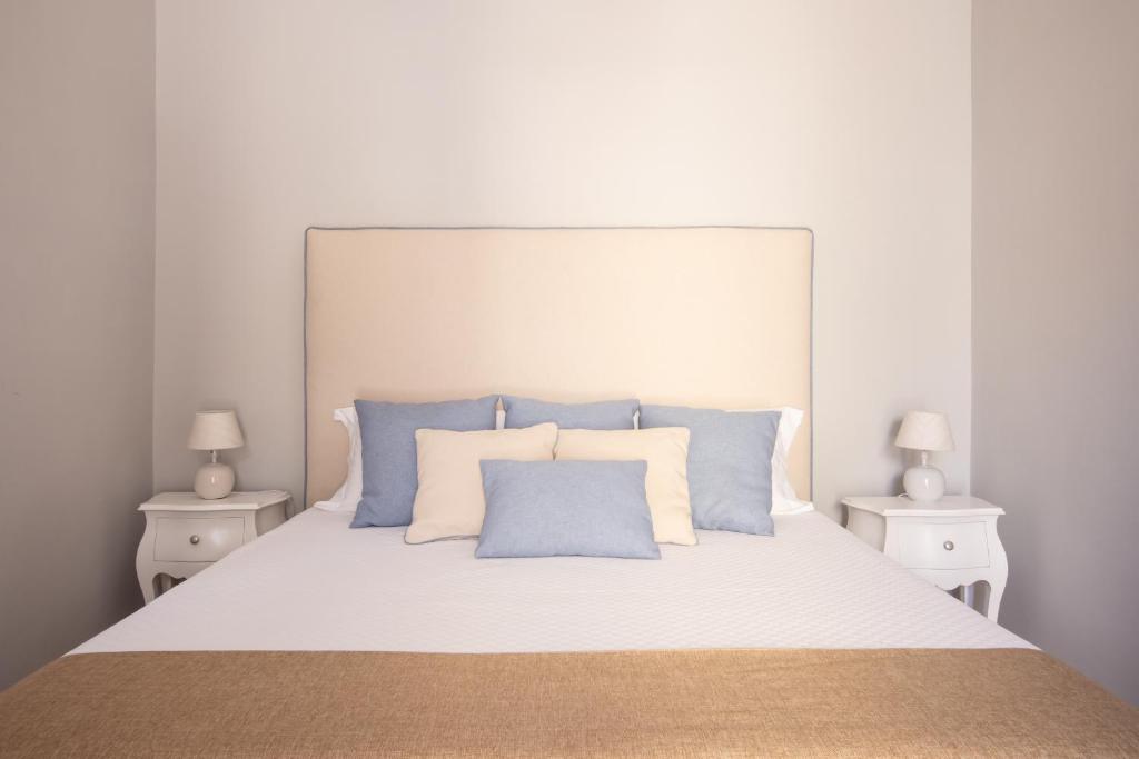 białe łóżko z białymi i niebieskimi poduszkami w obiekcie 4711 Boutique Apartment w Sorrento