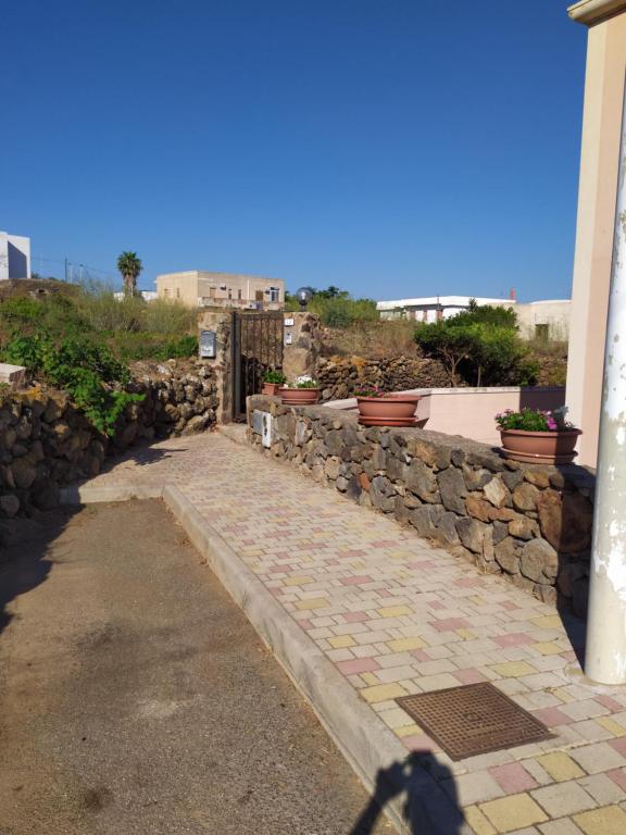 潘泰萊里亞的住宿－Azzurra’s House Pantelleria，石墙,上面有盆栽植物