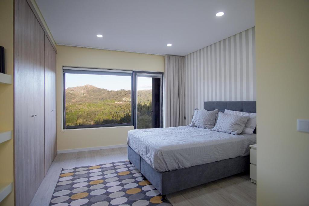 ein Schlafzimmer mit einem Bett und einem großen Fenster in der Unterkunft Quinta do Além 