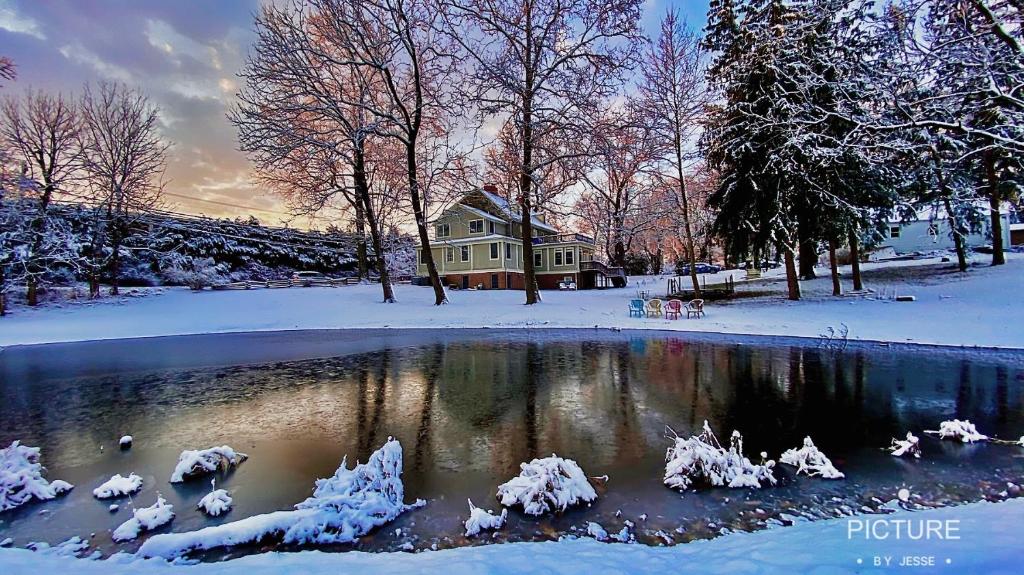 a house in the snow with a pond in front at Wayside Inn Bed and Breakfast in Ellicott City