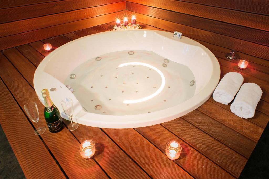 a bath tub in a wooden floor with candles and wine glasses at ADC Design Apartmány in Brno