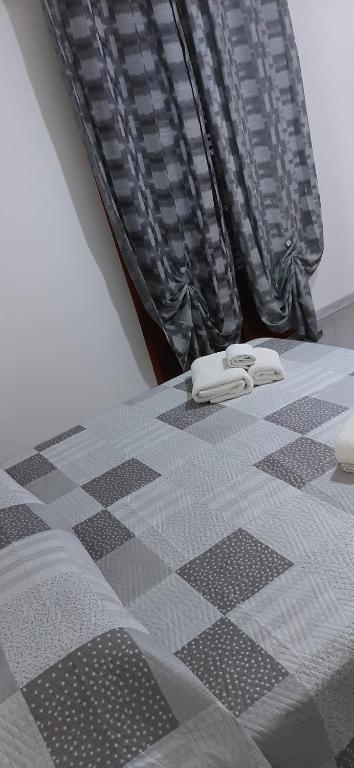 ein schwarz-weißes, kariertes Bett mit zwei Handtüchern darauf in der Unterkunft Casa vacanza il fiore in Castelbuono