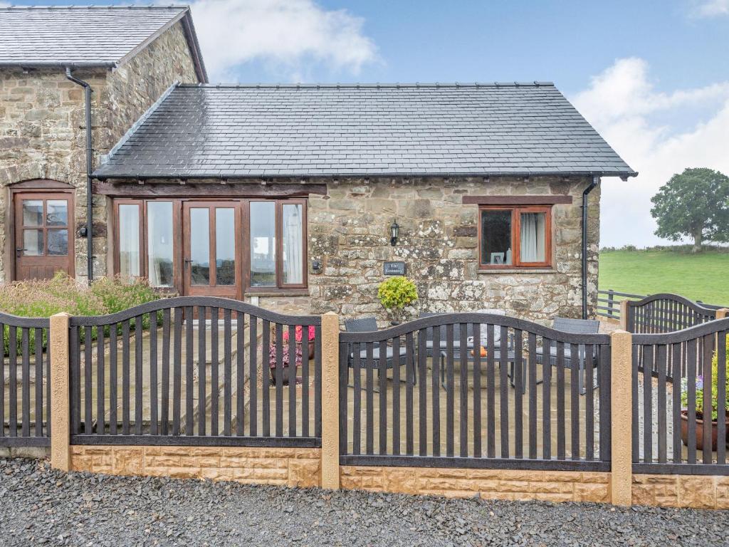 a wooden fence in front of a stone house at The Granary in Llanfair Caereinion
