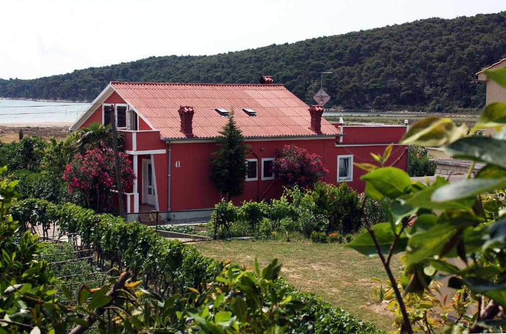a red house in front of a vineyard at Apartment Kampor 4972b in Kampor