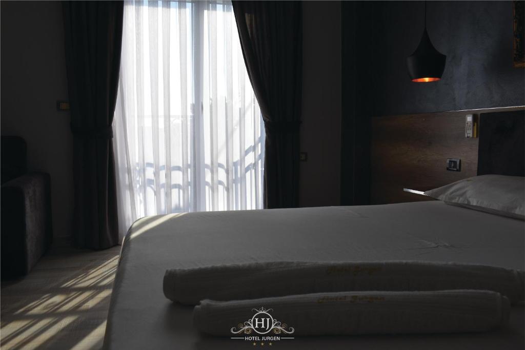 a bedroom with a bed and a large window at Hotel Jurgen in Lezhë