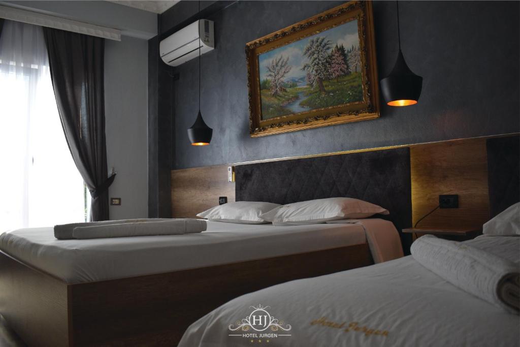 two beds in a hotel room with a picture on the wall at Hotel Jurgen in Lezhë