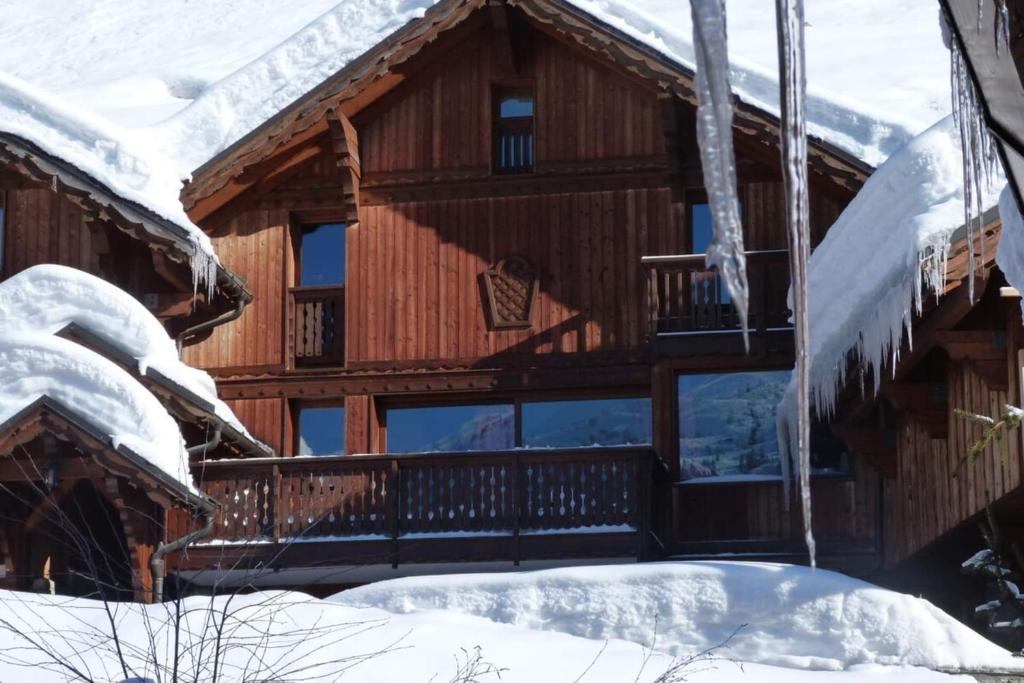 a log cabin with a balcony in the snow at Chalet Clearmount with Spa in Méribel