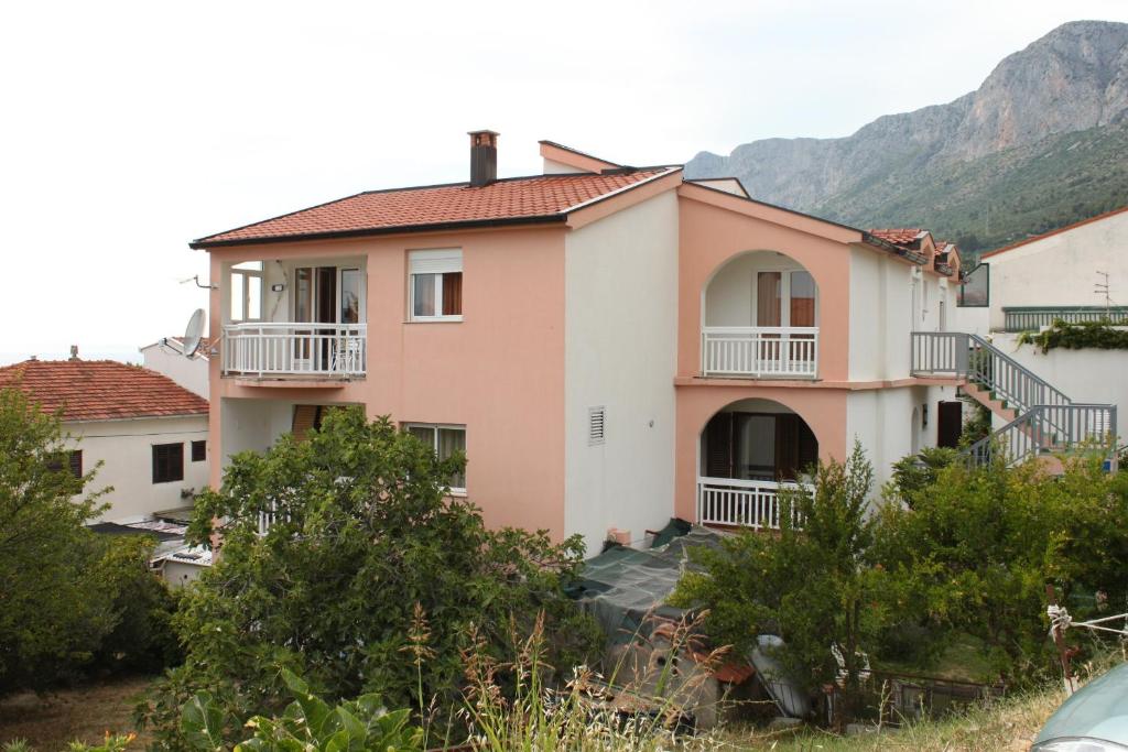 a house on a hill with mountains in the background at Apartments with a parking space Gradac, Makarska - 6820 in Gradac
