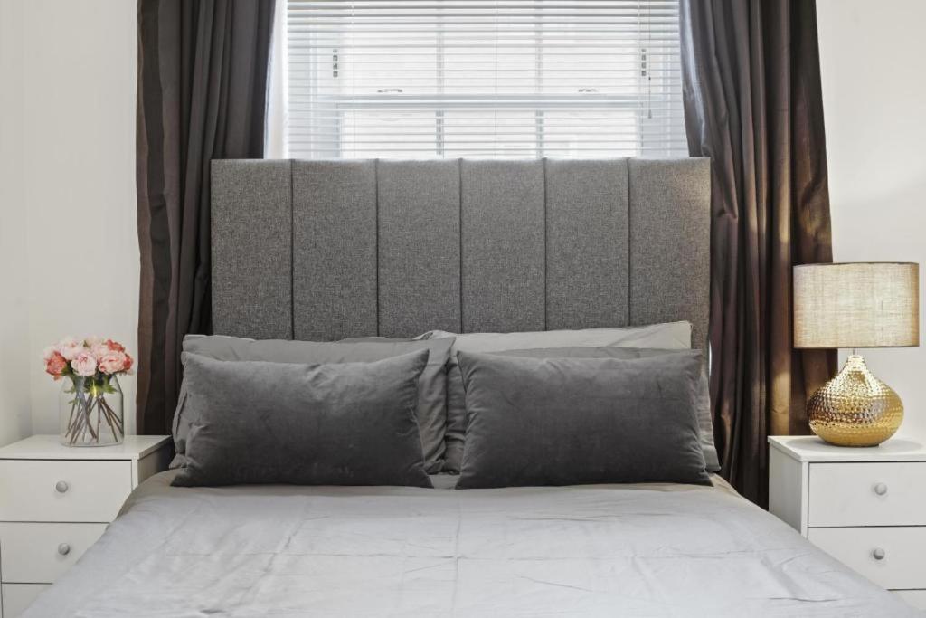 a bed with gray pillows and a window in a bedroom at Modern Deluxe Apartment London Camberwell Denmark in London