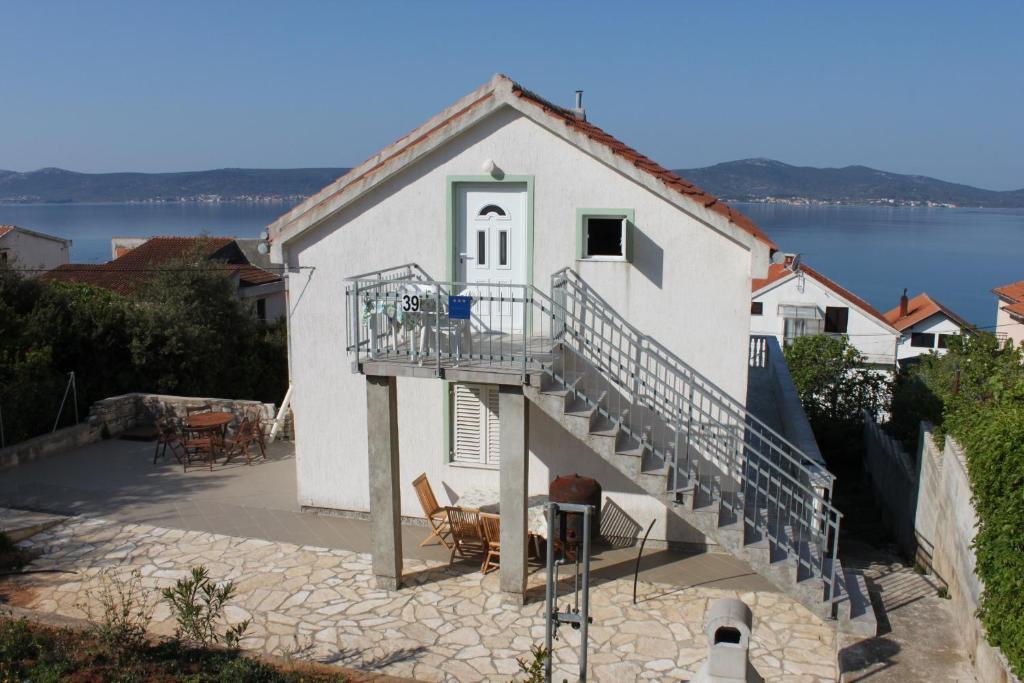 a white building with a staircase next to a lake at Apartments with a parking space Sveti Petar, Biograd - 3251 in Sveti Filip i Jakov