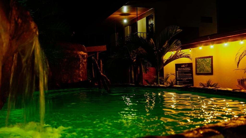 a swimming pool with a water fountain at night at Cabinas Colibri in Fortuna