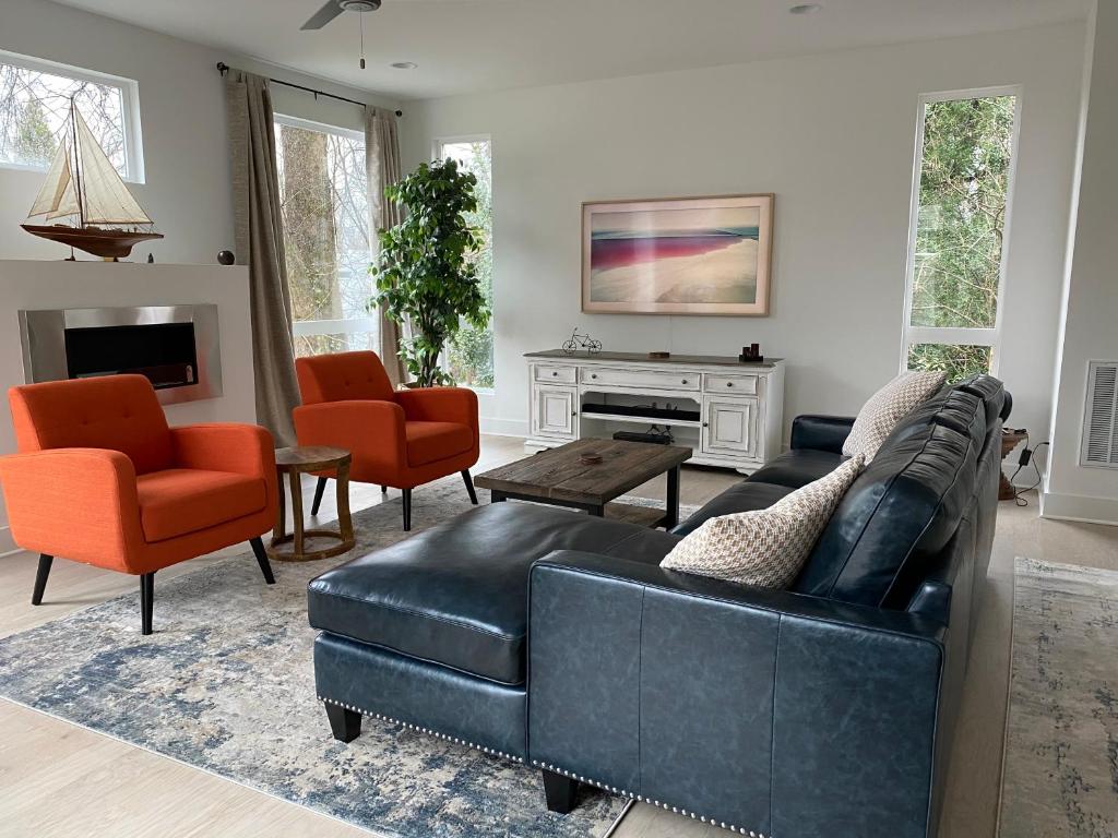uma sala de estar com um sofá de couro preto e cadeiras em Entire Home Close to BOA Stadium & City em Charlotte