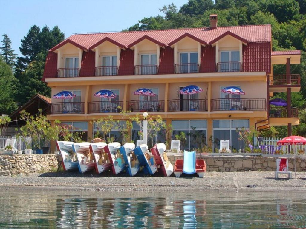 a building with a bunch of chairs in front of the water at Villa Cvet Rooms in Ohrid