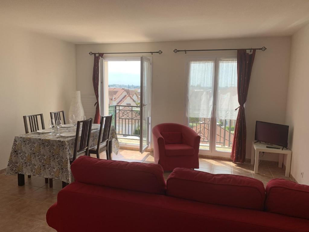 a living room with a red couch and a dining room table at Appartement Dives-sur-Mer, 2 pièces, 4 personnes - FR-1-487-236 in Dives-sur-Mer
