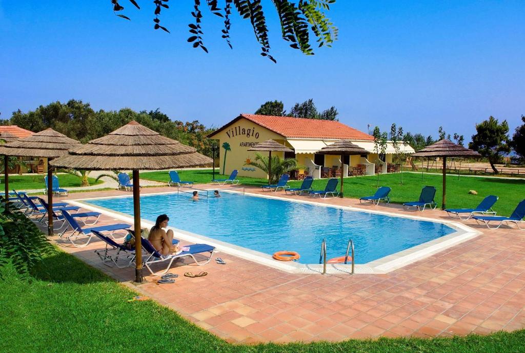 una mujer sentada en sillas junto a una piscina en Villagio en Lefkada