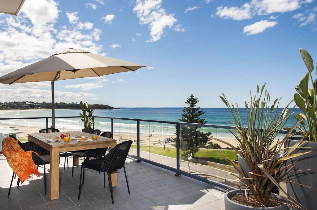 a patio with a table with an umbrella and the beach at The Penthouse in Mollymook