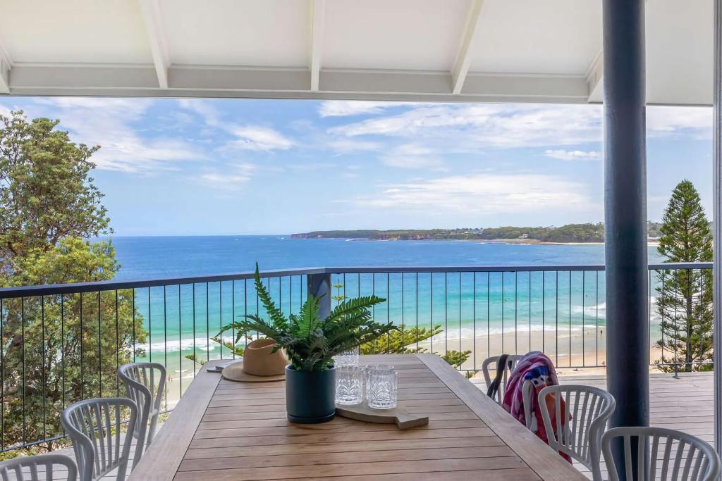 a table on a balcony with a view of the ocean at Northstar on Mollymook Beach in Mollymook